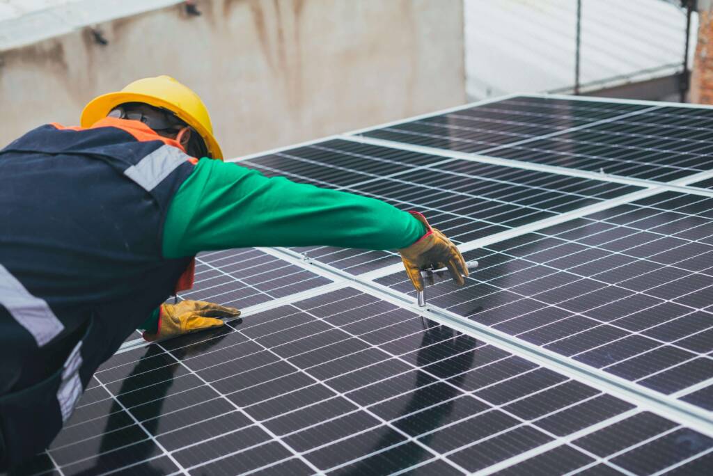 Homem prestando serviço de instalação de painel fotovoltaico para uma administradora de condomínios