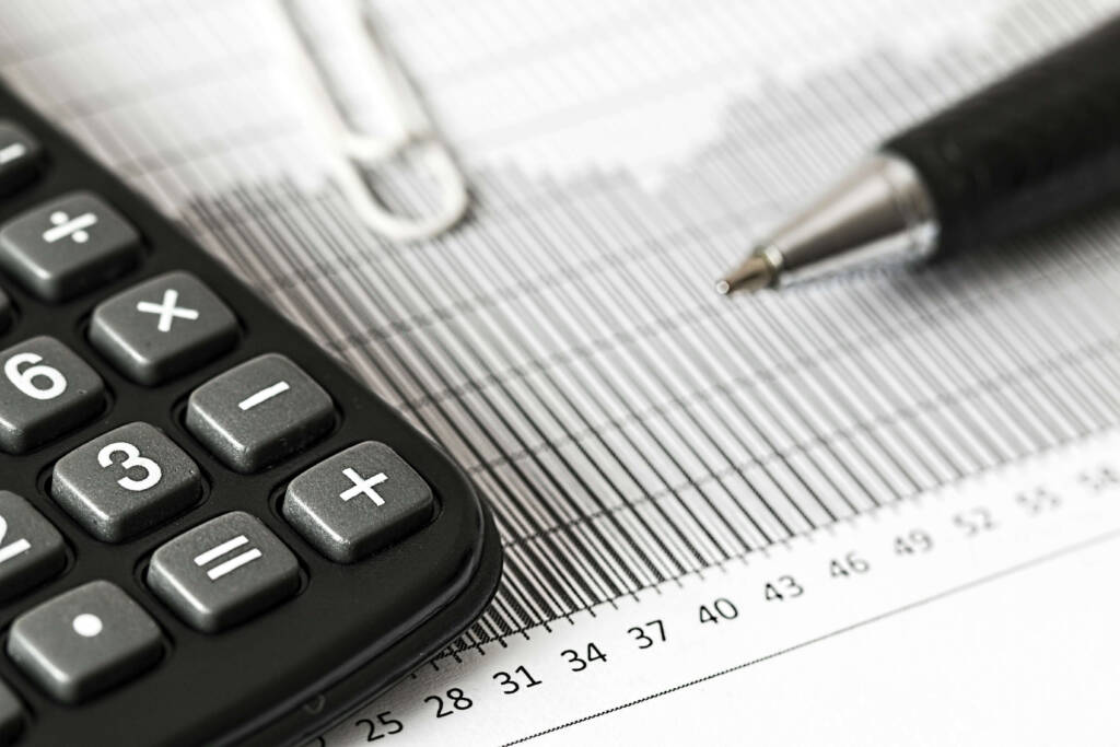 Imagem de uma calculadora e uma caneta em cima de uma planilha, represetando os cortes de gastos que podem vir ao contratrar a Portaria Porter
