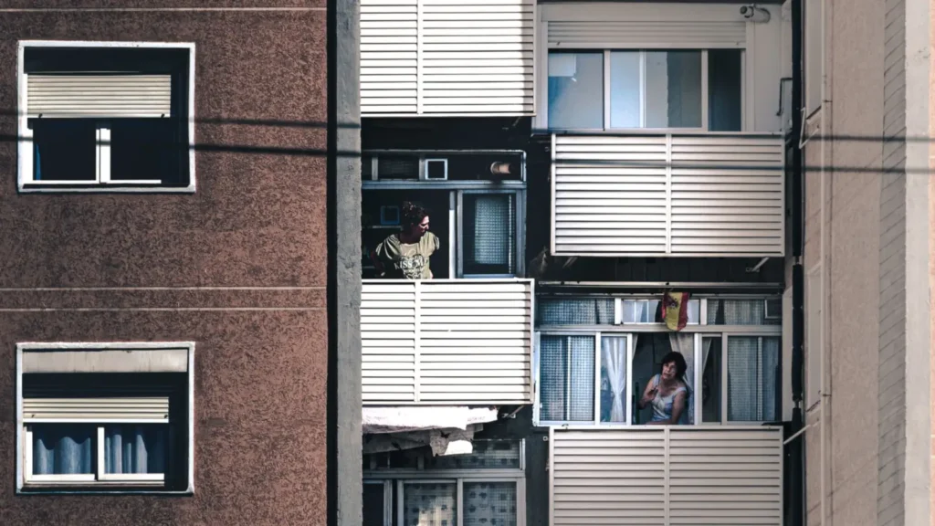 Vizinhos conversam de suas varandas, gesto simples de convivência que define um condomínio afetivo