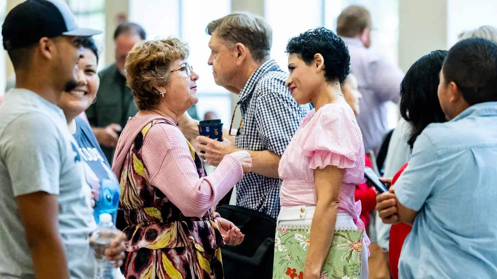 Síndico conversa com moradoras em encontro no salão, liderança próxima que sustenta um condomínio afetivo